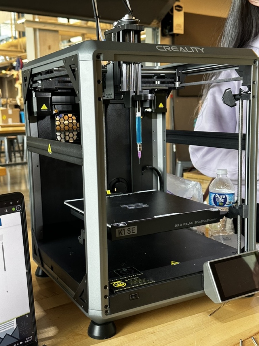 A finished bioprinter on a lab bench, with a syringe of alginate bioink mounted